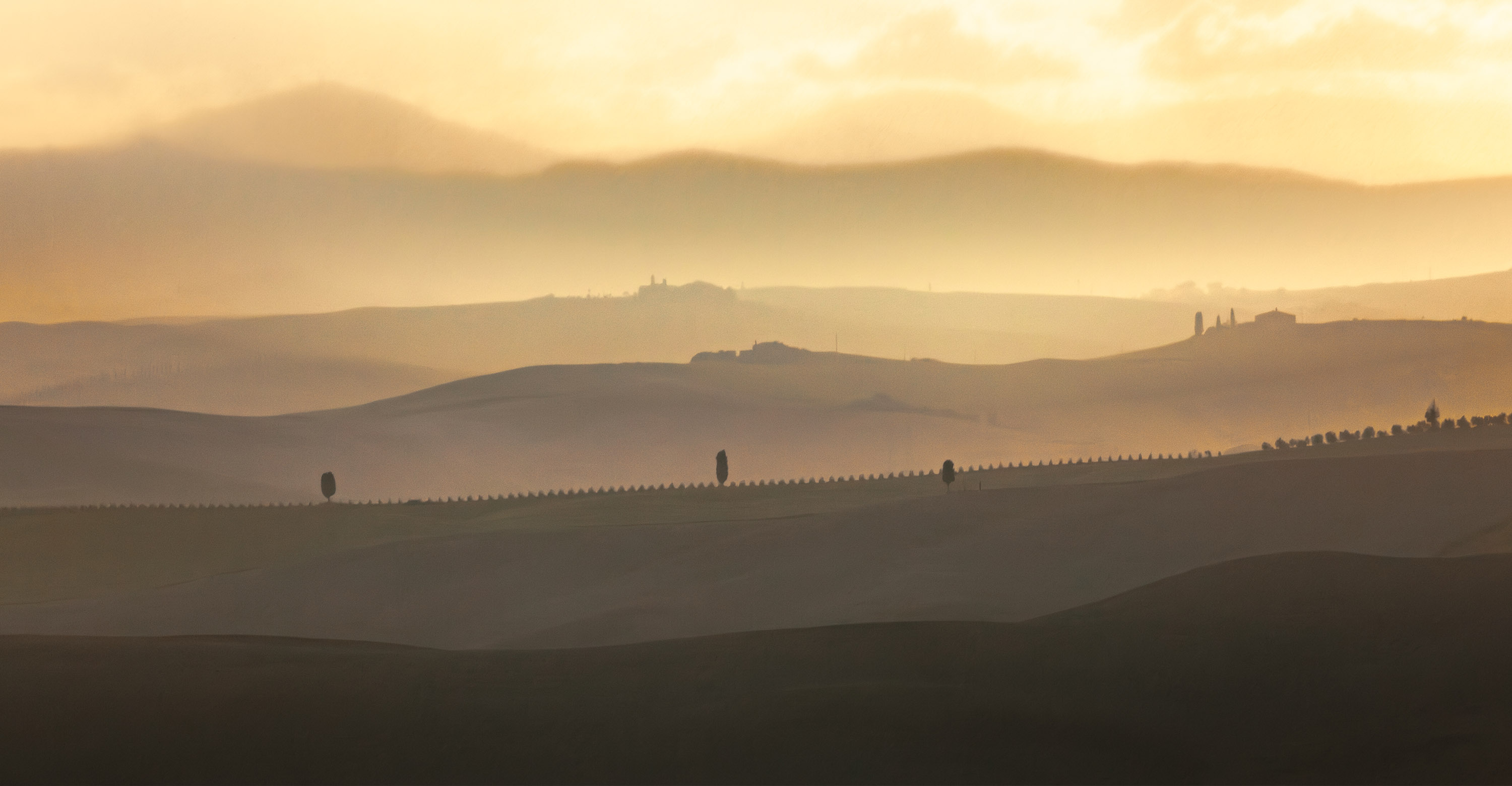 Tuscan sunset with fog, rolling hills and cypress en it